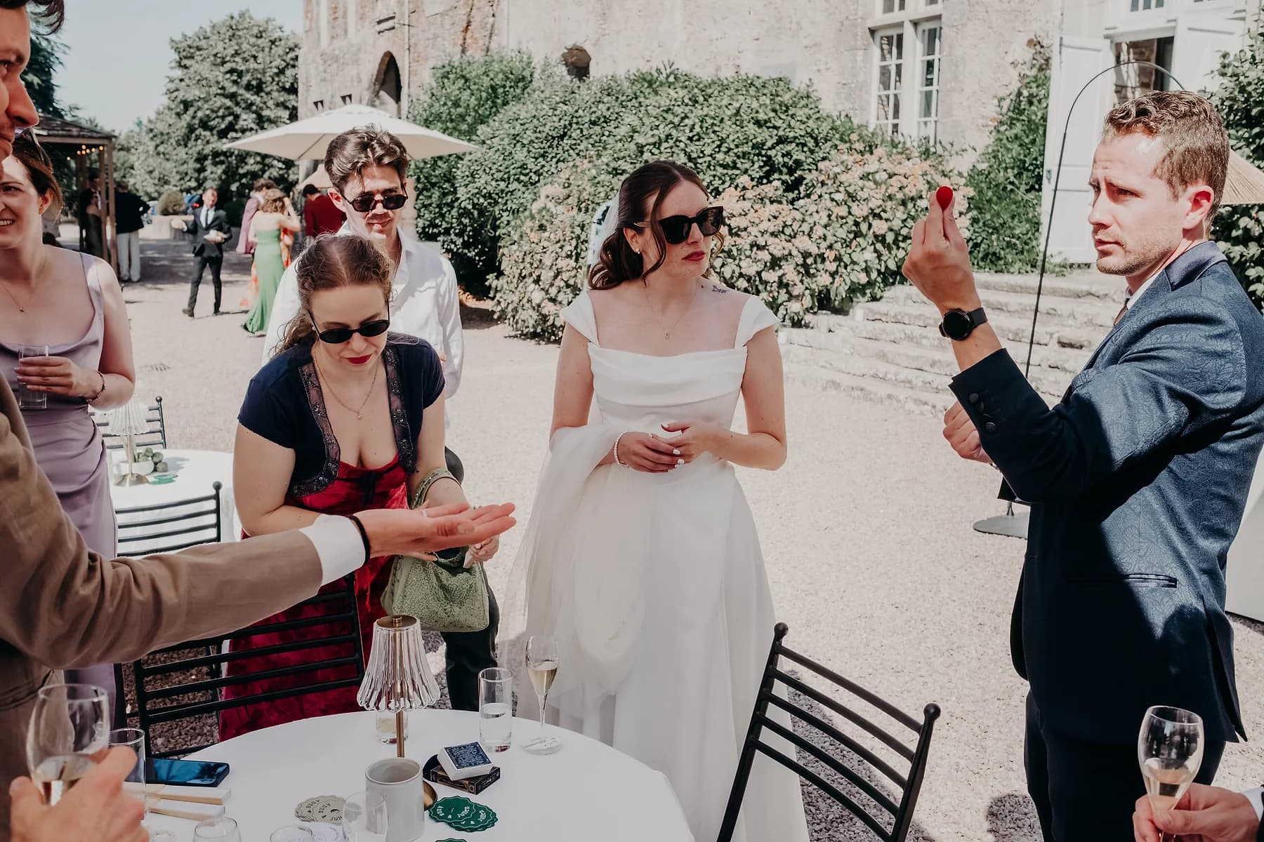 Un tour se joue au milieu d'un groupe d'invités, devant un château